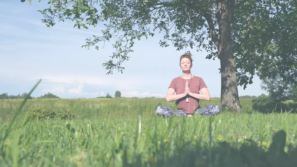 Die Yoganomadin im Schneidersitz bei der Meditation in der Natur, ihre Hände in Anjali Mudra gefaltet.